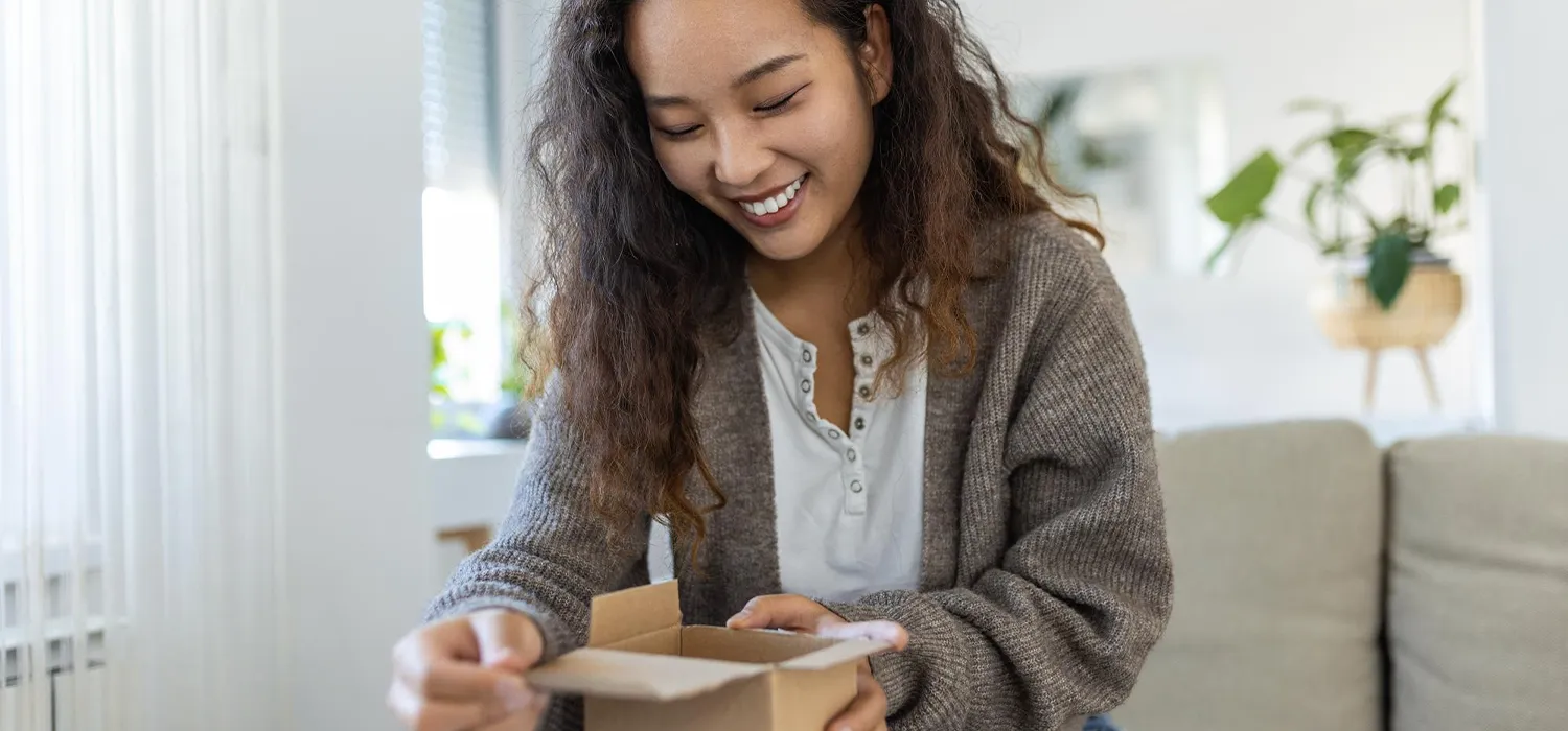 Cliente souriante ouvrant un colis après une commande en ligne