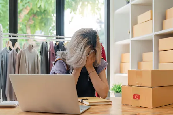 Commerçante en ligne stressée devant son ordinateur à cause d’un manque de ventes sur sa boutique e-commerce.